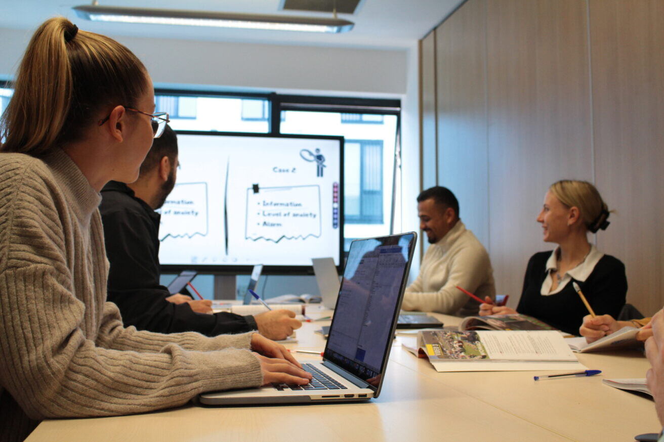 A team of professionals in a classroom. One woman is working on a laptop.