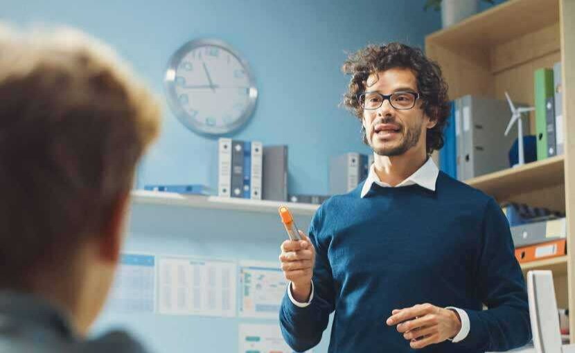 kind looking teacher gesturing in front of class.